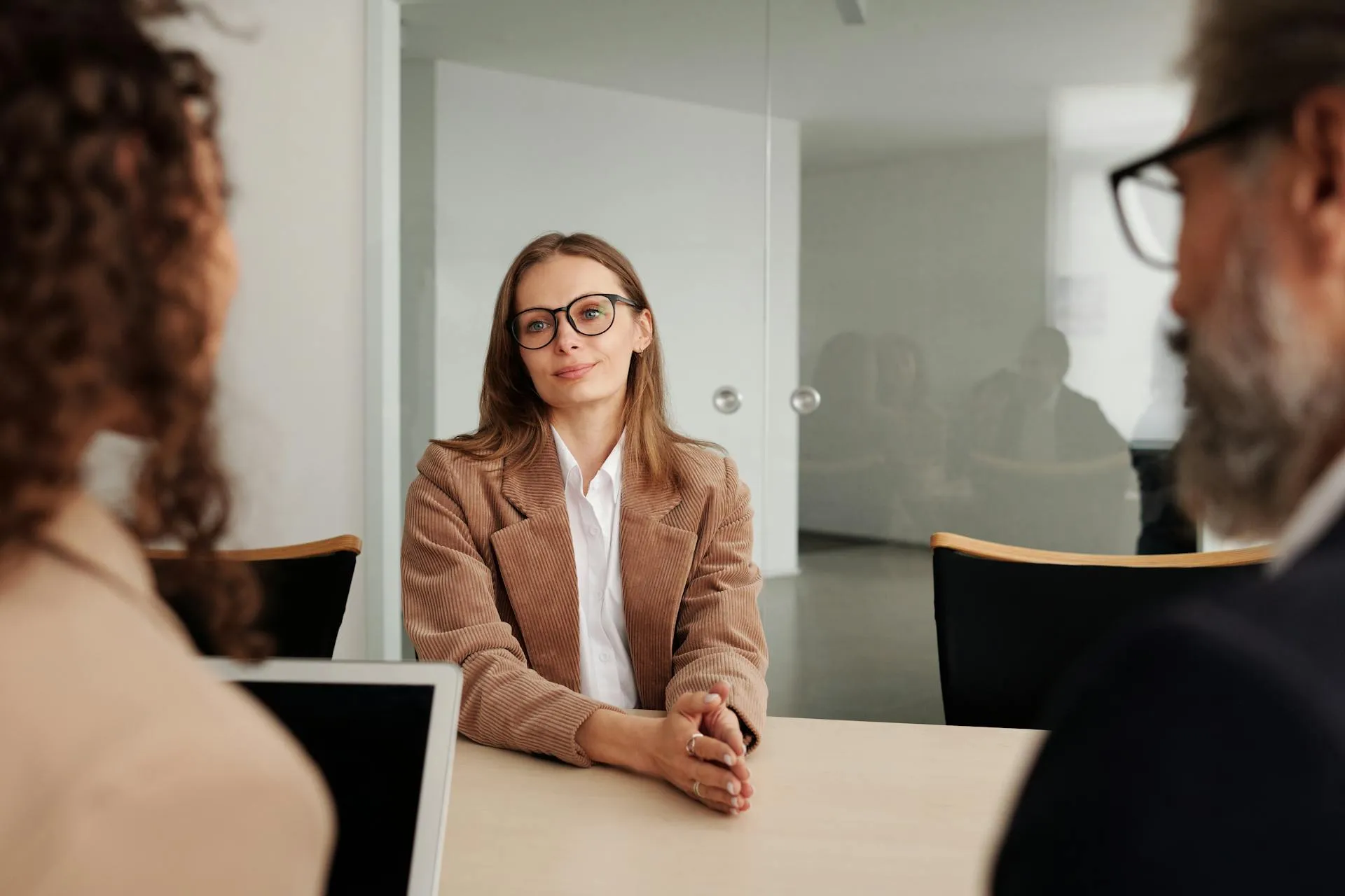 A candidate speaking with two interviewers seated across a conference table
